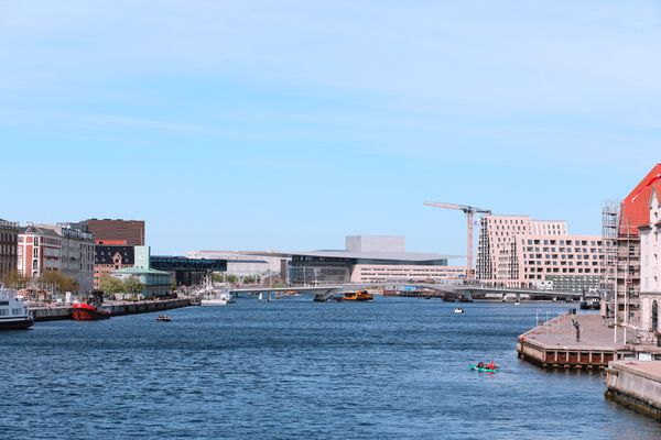 A photo of the harbour, showing the Opera House in the distance, and two people kayaking closer to the camera